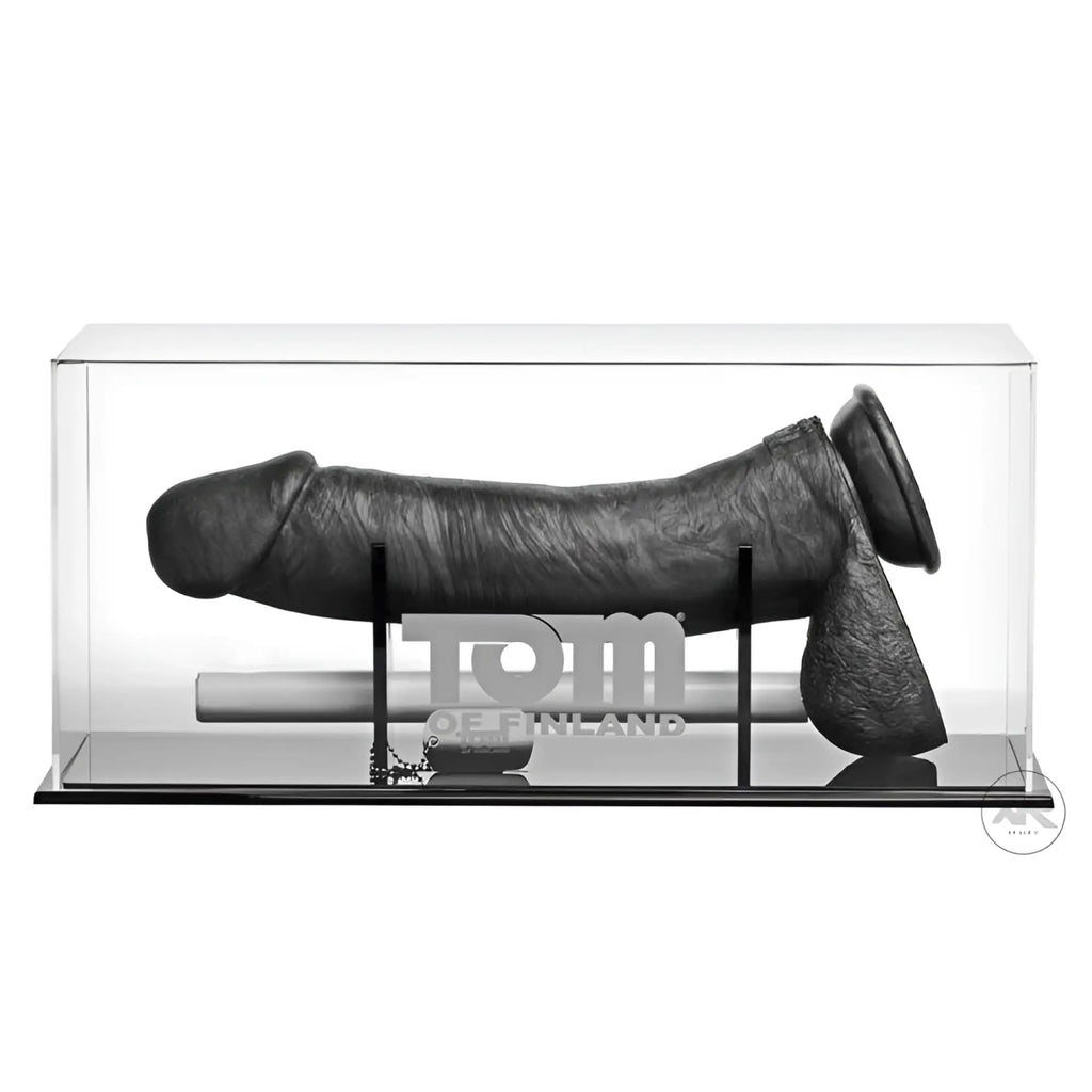 A 12-inch black textured Tom of Finland Kake Cock silicone dildo displayed horizontally in a clear acrylic case.