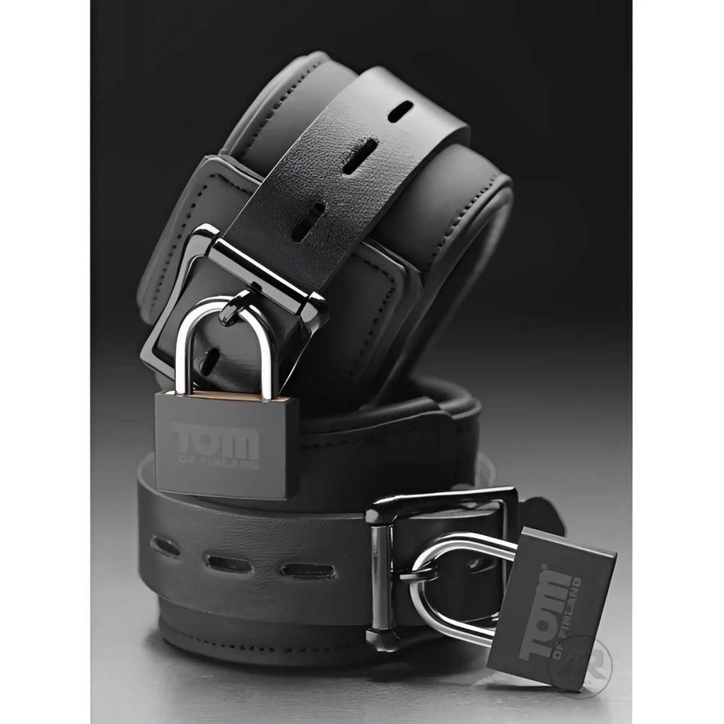 Tom of Finland black neoprene wrist cuffs with adjustable straps, silver buckles, and branded silver padlocks.