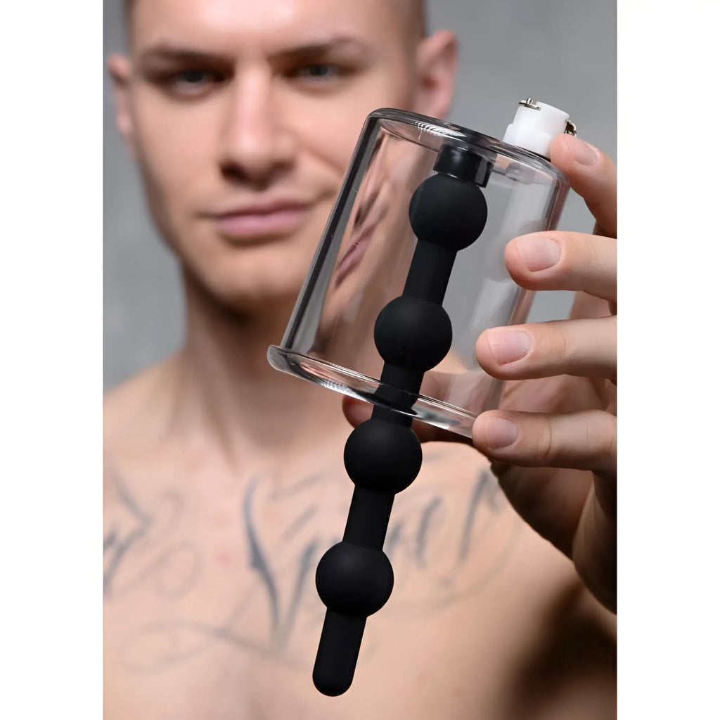 Tom of Finland Rosebud Cylinder: A clear plastic canister featuring a black, beaded silicone insert held by a man.