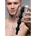 Tom of Finland Rosebud Cylinder: A clear plastic canister featuring a black, beaded silicone insert held by a man.
