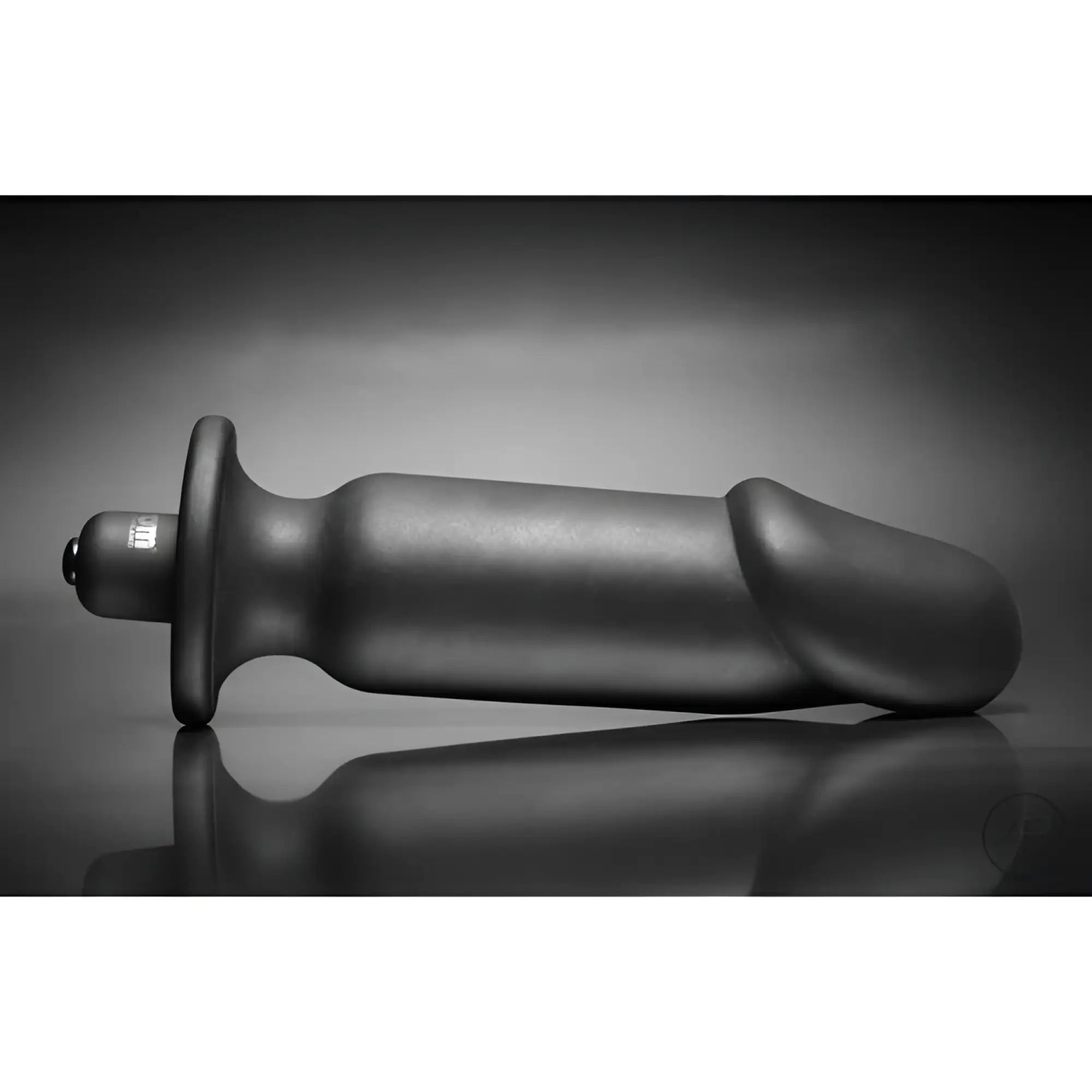 Black silicone Tom of Finland vibrating anal plug with a flared base, shown in profile against a dark background.