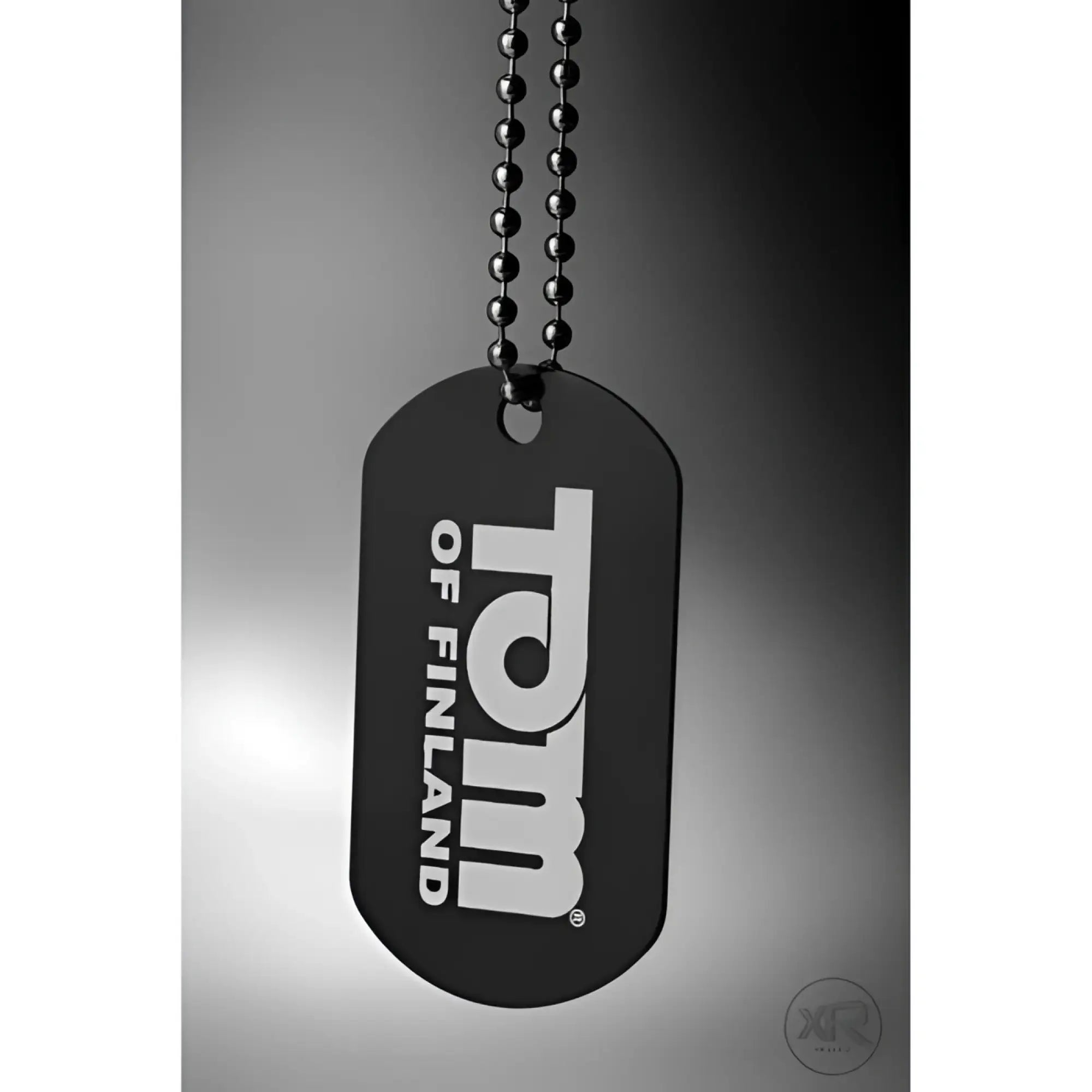 Black Tom of Finland branded dog tag necklace hanging against a grey background.
