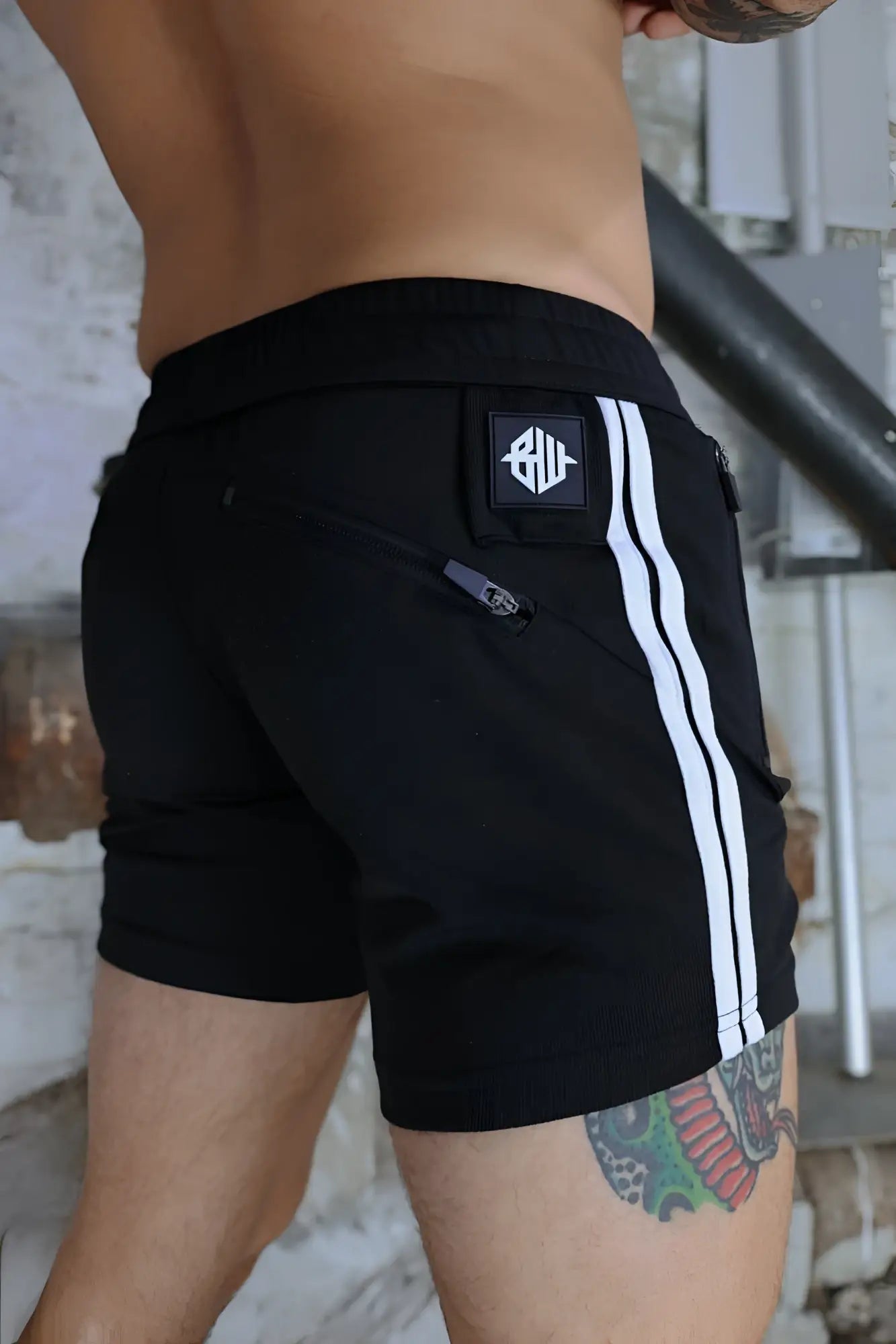Black trade trainer shorts with two white stripes and a logo patch on the back waistband