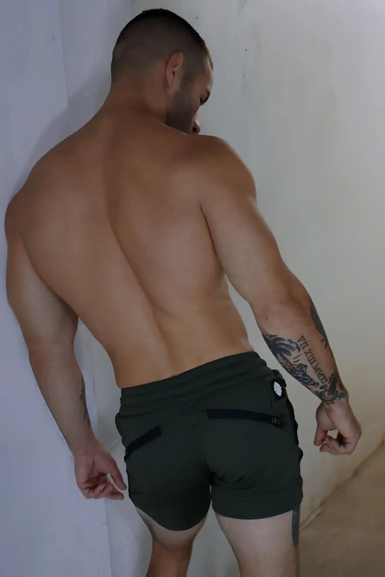 Trade trainer shorts in dark green with black zipper pockets and a white button detail on the back waistband