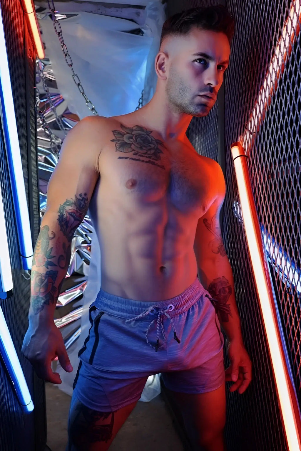 The man is wearing light blue trade trainer shorts with black side stripes and a drawstring waistband