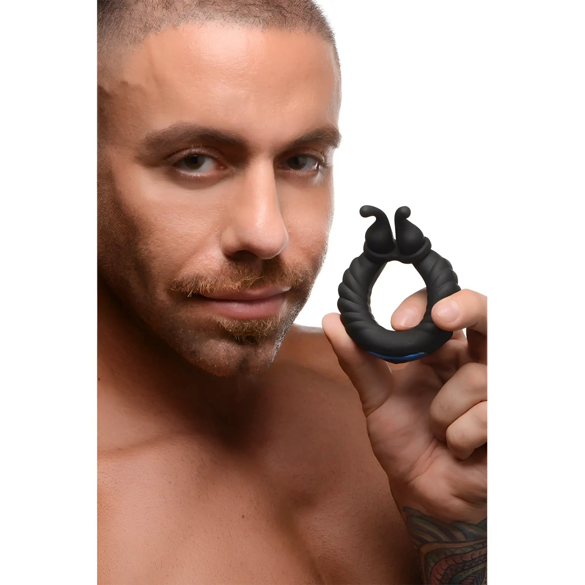 A man holds a black, ribbed Trinity Men 10X Cobra silicone dual stimulation cock ring with small top protrusions.