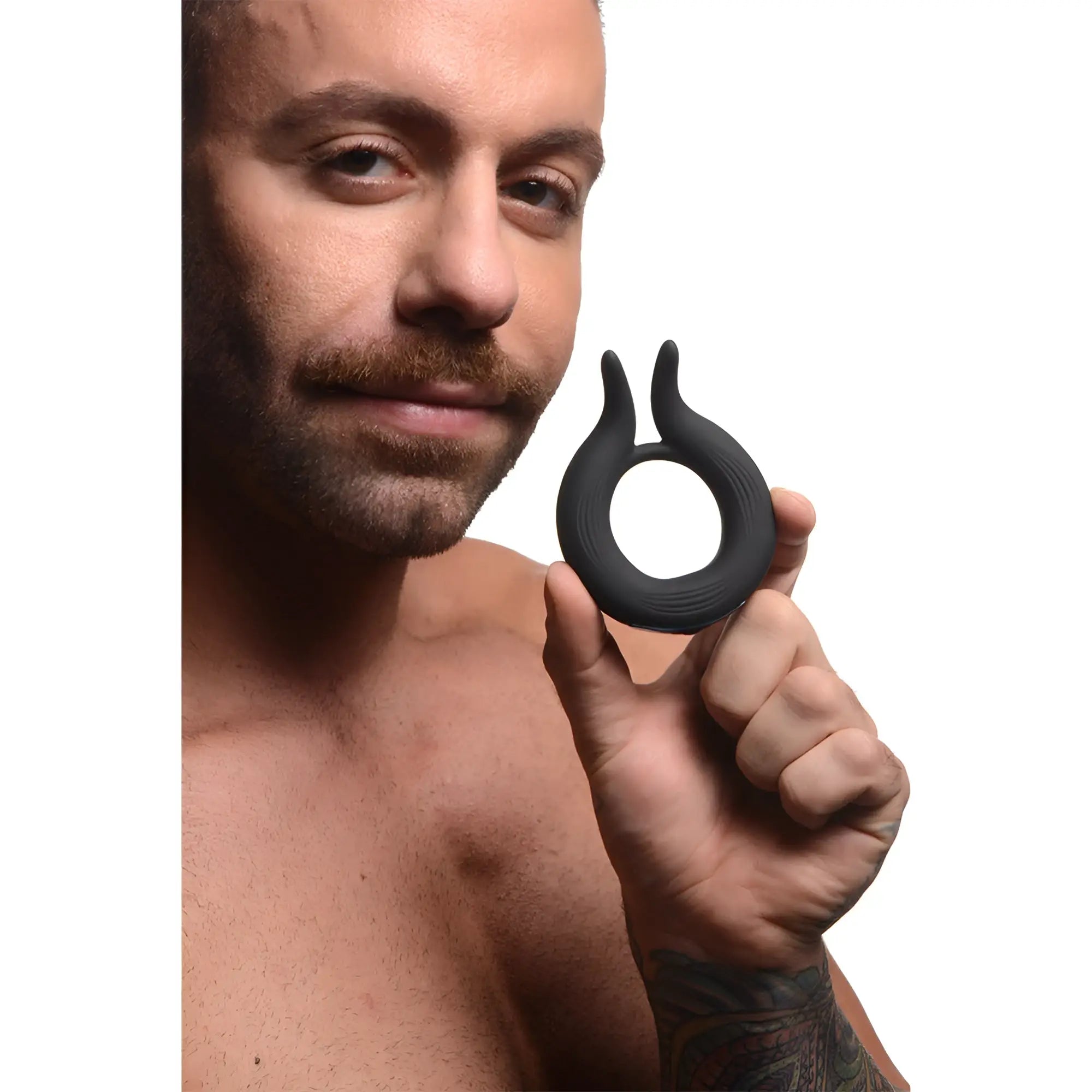 A man holding a black Trinity Men 10X Dual Stim silicone cock ring with a textured design against a white background.