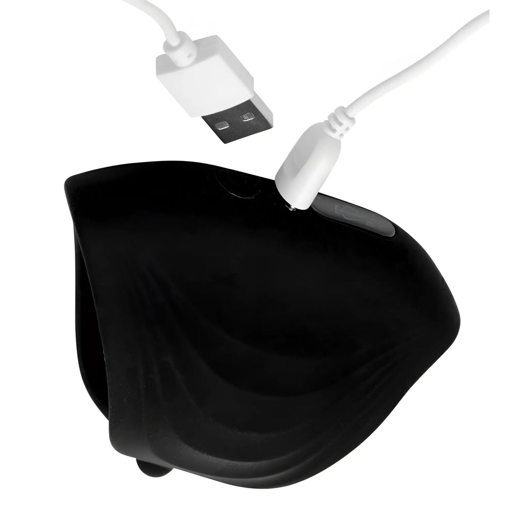 Trinity Men 10X Pleasure Stroke silicone penis sleeve in black with a white magnetic charging cable attached.