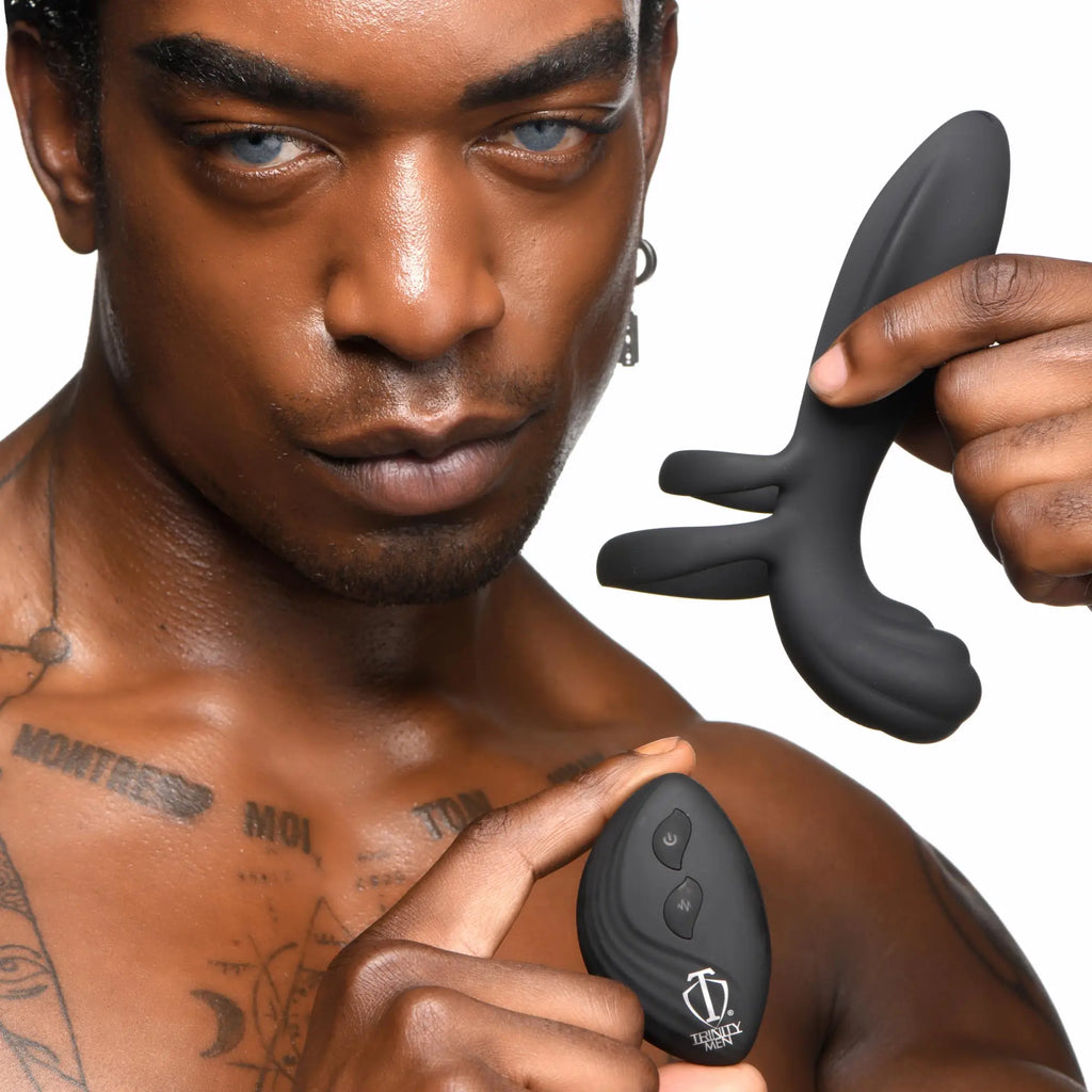 A man holds a black silicone Trinity Men girth enhancer and its matching remote control against a white background.