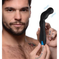 A man holds a black, curved silicone Trinity Men 12X prostate vibrator featuring blue accents and motion lines.