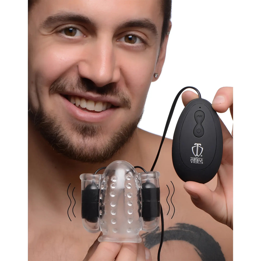 Trinity Men 20X Deluxe Dual Vibrating Head Teaser: A man holds a clear, textured vibrator with a black control remote.