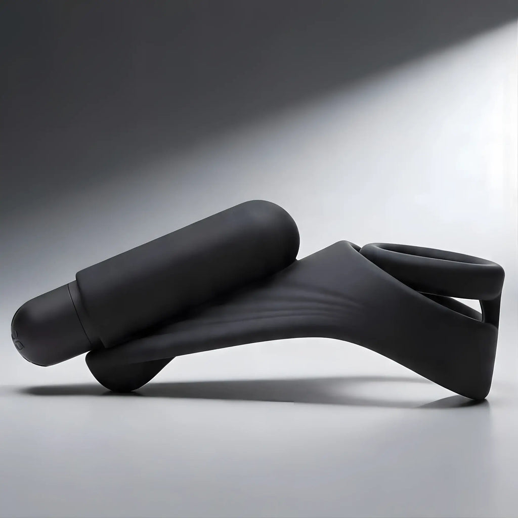 Trinity Men 7X matte black silicone C-ring with a contoured, vibrating taint stimulator, shown from the side.