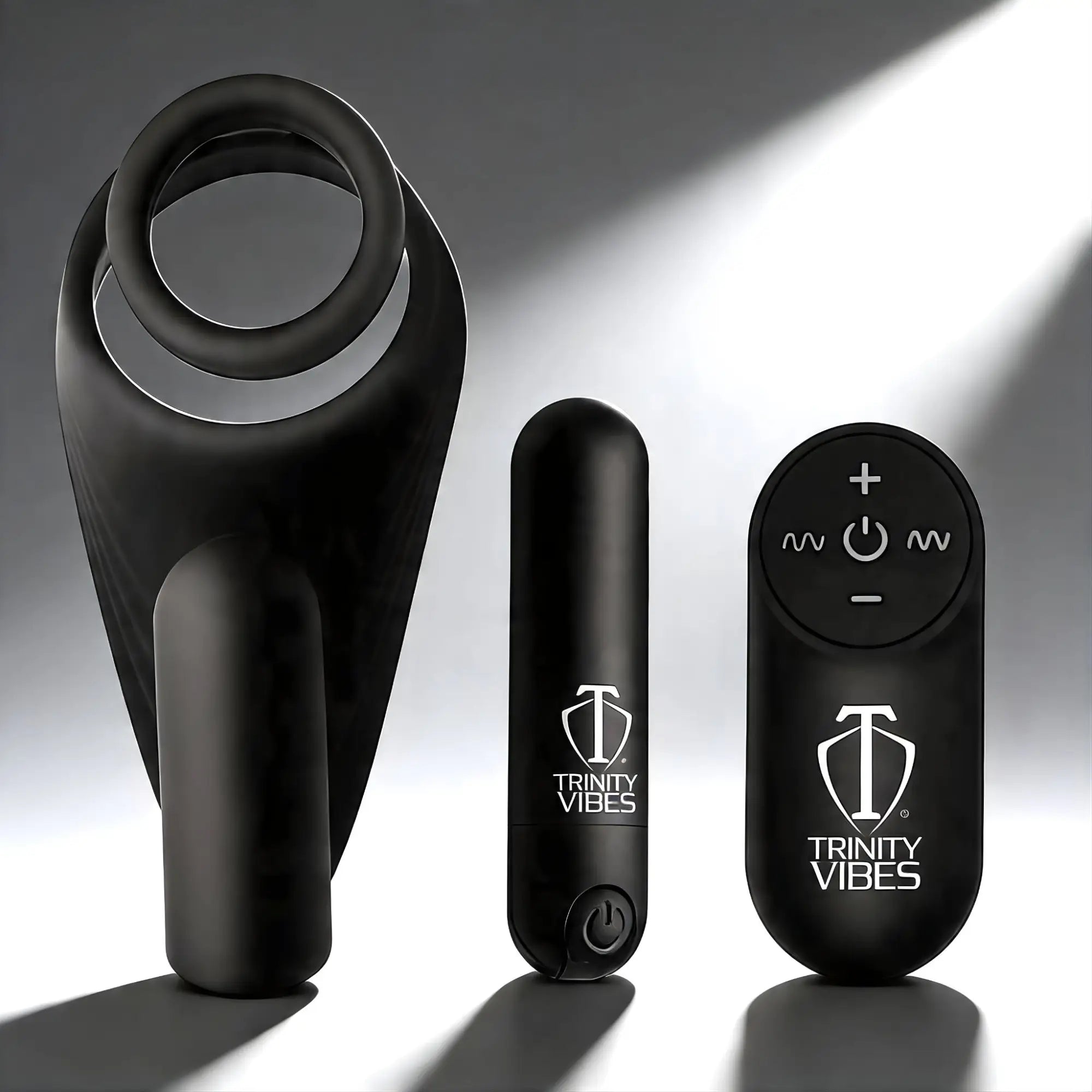 Trinity Men 7X black silicone c-ring with vibrating stimulator, power bullet, and remote control on a grey background.