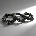 Three black Trinity Men Erection Enhancement rings with beaded, textured designs arranged on a light gray surface.