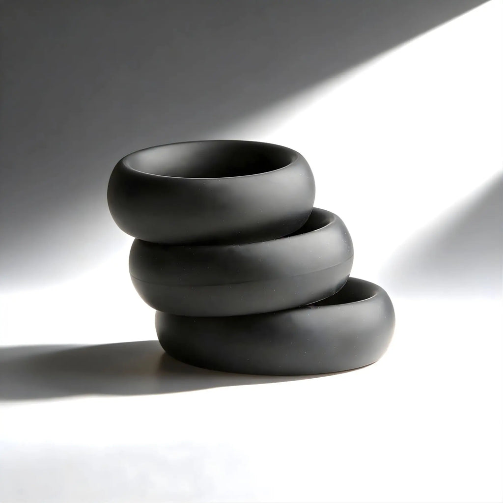 Trinity Men Fat Silicone Cock Ring 3-Pack: Three smooth, matte black, thick silicone rings stacked vertically.