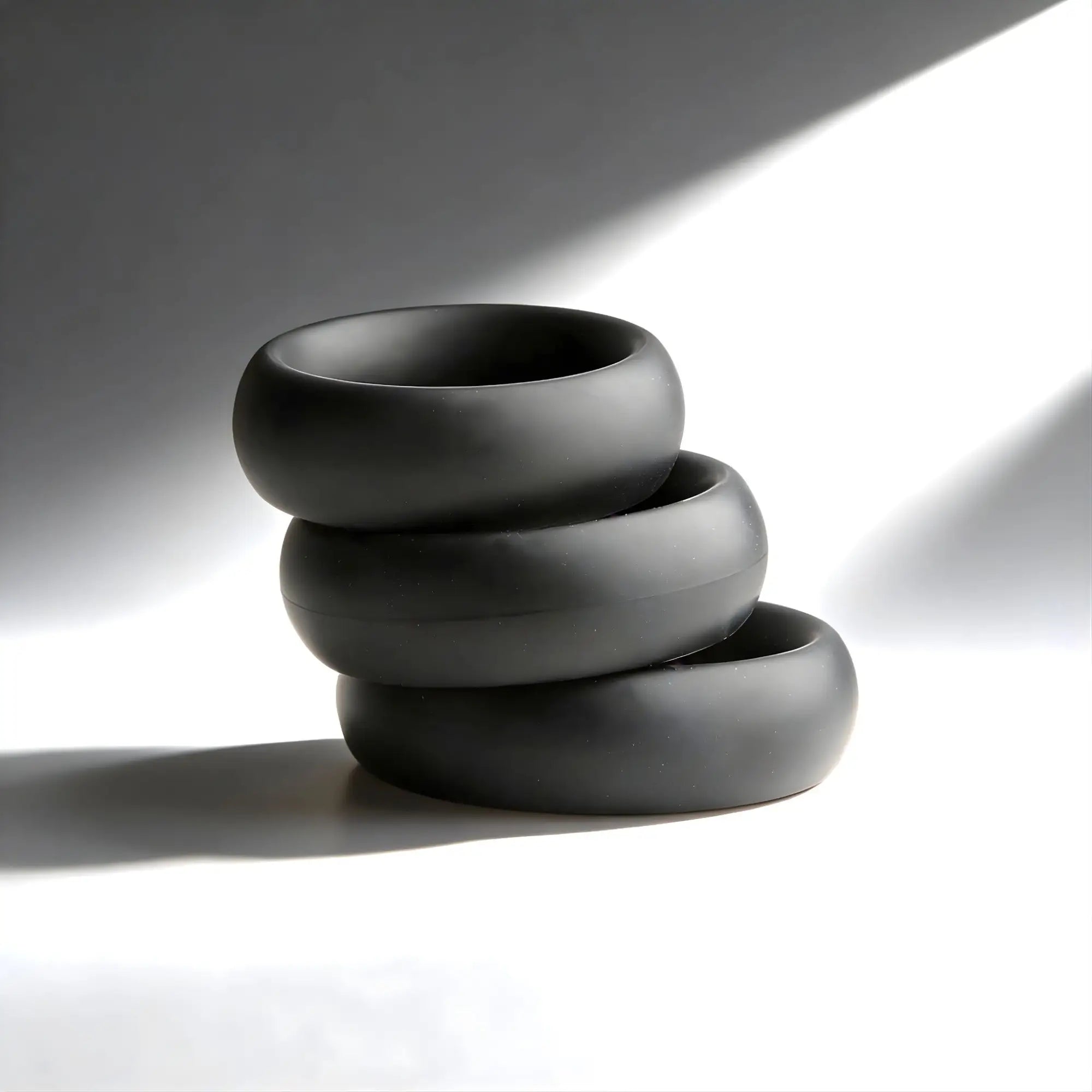Trinity Men Fat Silicone Cock Ring 3-Pack: Three smooth, matte black, thick silicone rings stacked vertically.