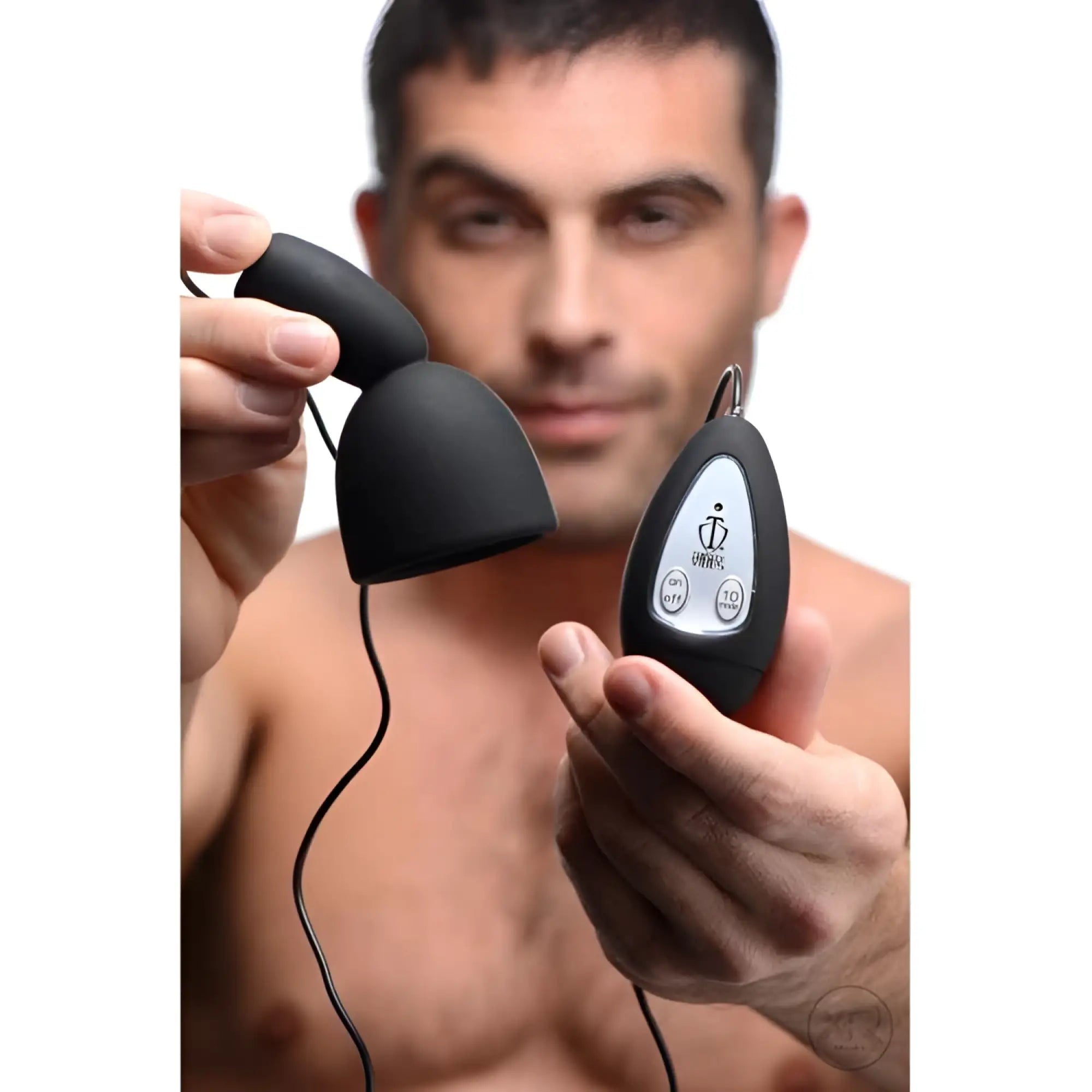 A man holds a black, 10-speed Trinity Vibes silicone penis head teaser with a matching wired remote control.