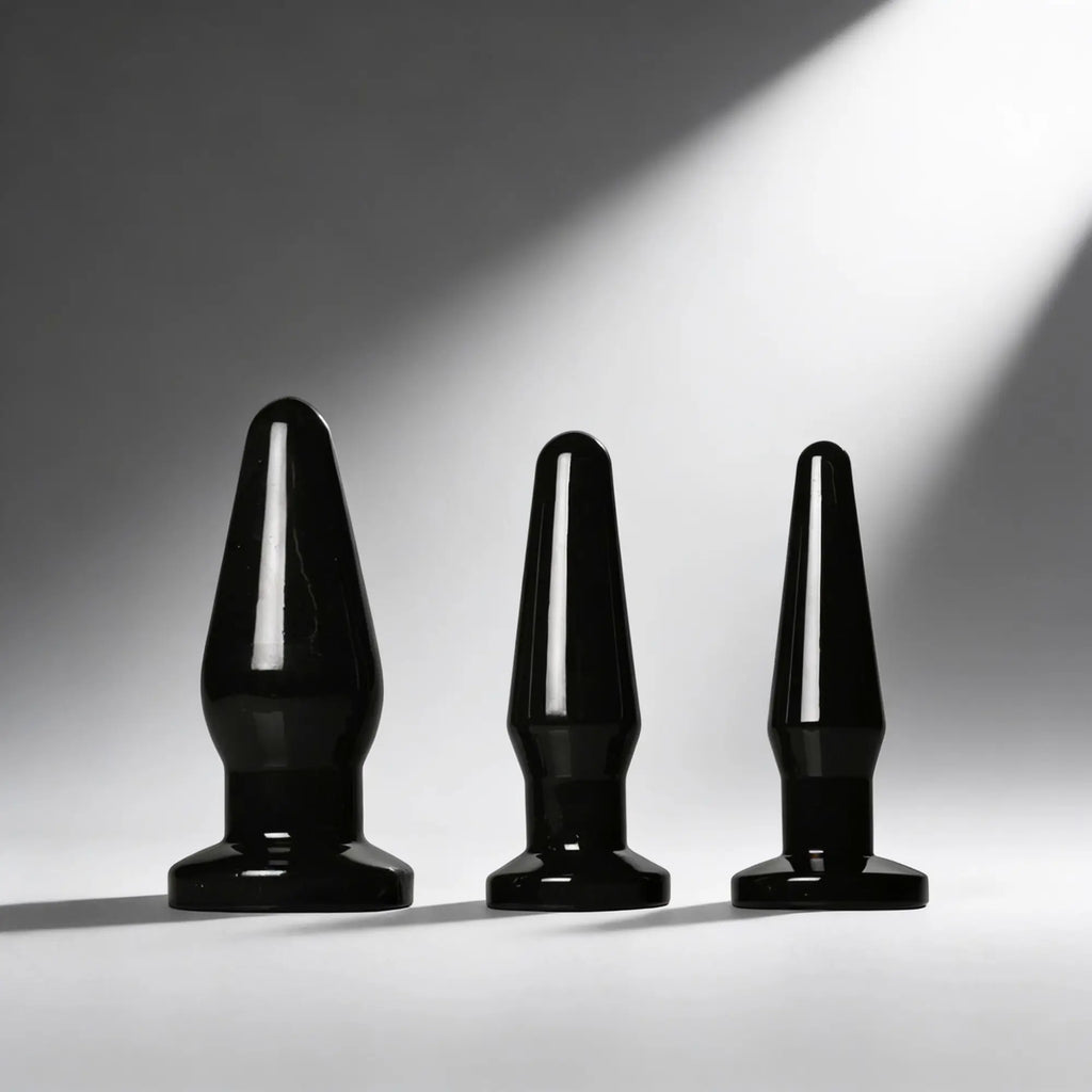 Trinity Vibes Anal Trainer Set: Three sleek, black, glossy anal plugs of varying sizes displayed against a gray background.