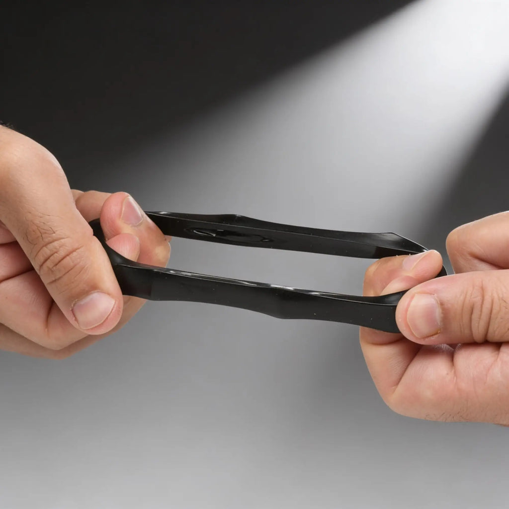 Hands stretching a black, flexible Trinity Vibes Hexnut cock ring, showing its durable, smooth silicone material.