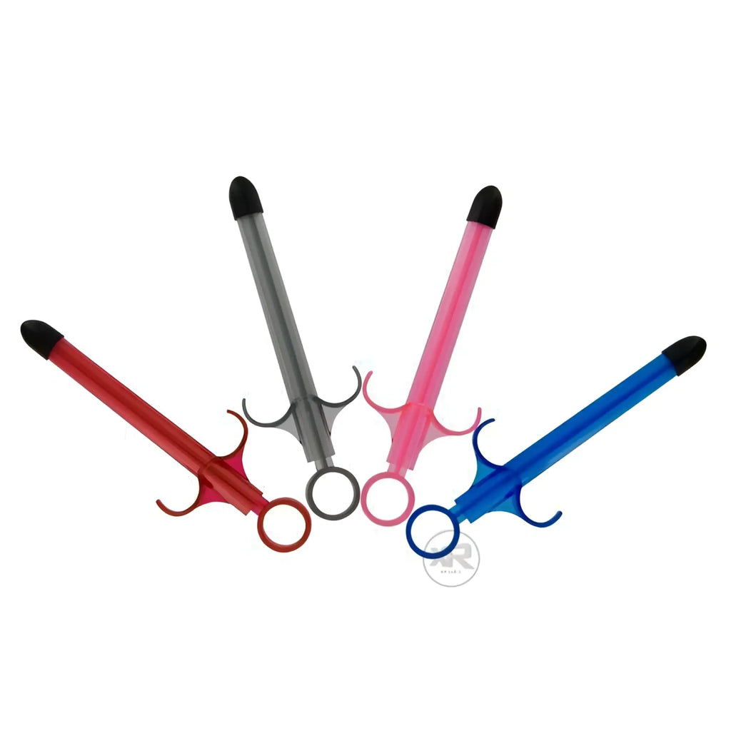 Four Trinity Vibes Lubricant Launchers in red, gray, pink, and blue, featuring syringe-style designs with black tips.