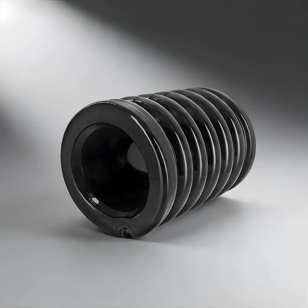 Trinity Vibes Stretch-To-Fit Cock Cage: A smooth, black, cylindrical, accordion-style silicone sleeve on a gray background.