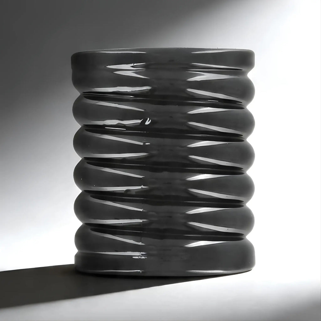 Trinity Vibes Stretch-To-Fit cock cage: a dark gray, cylindrical sleeve with a ribbed, accordion-style texture.