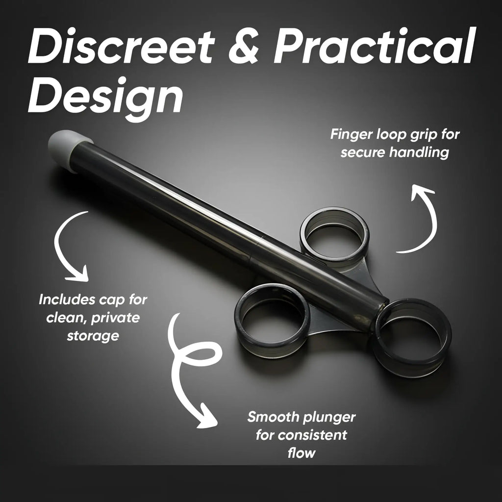 Black Trinity Vibes XL lubricant launcher with a finger-loop grip, plunger, and storage cap against a dark background.