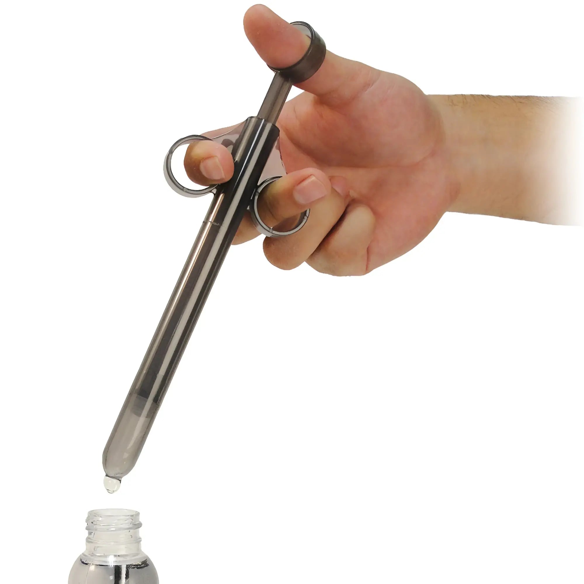 A hand holds a translucent, smoky-grey Trinity Vibes XL lubricant launcher, dripping liquid into a small bottle below.