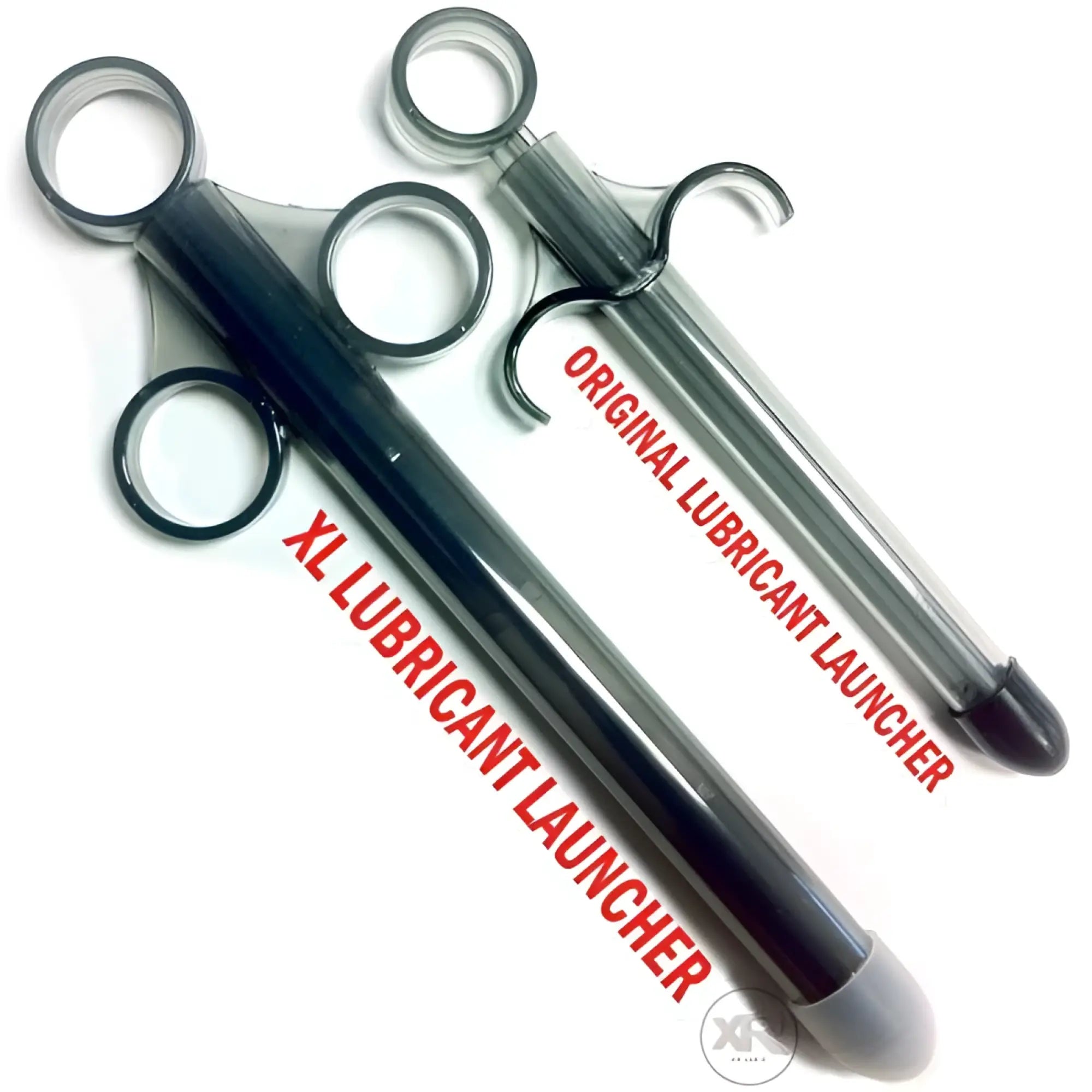 Two Trinity Vibes lubricant launchers, XL and original size, shown as translucent black, syringe-style applicators.