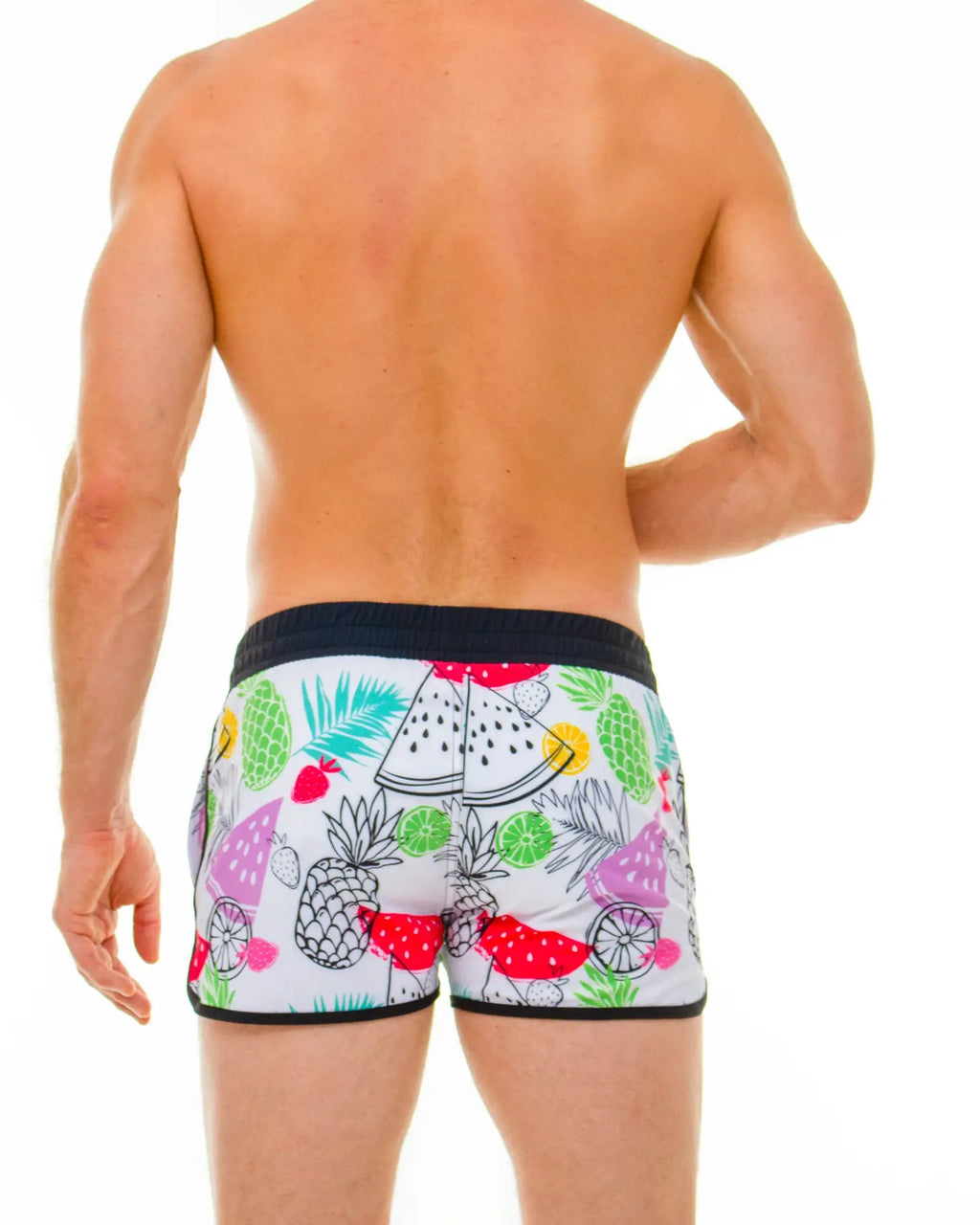 White swim trunks with vibrant tropical fruit pattern of pineapples watermelons and limes in bright colors