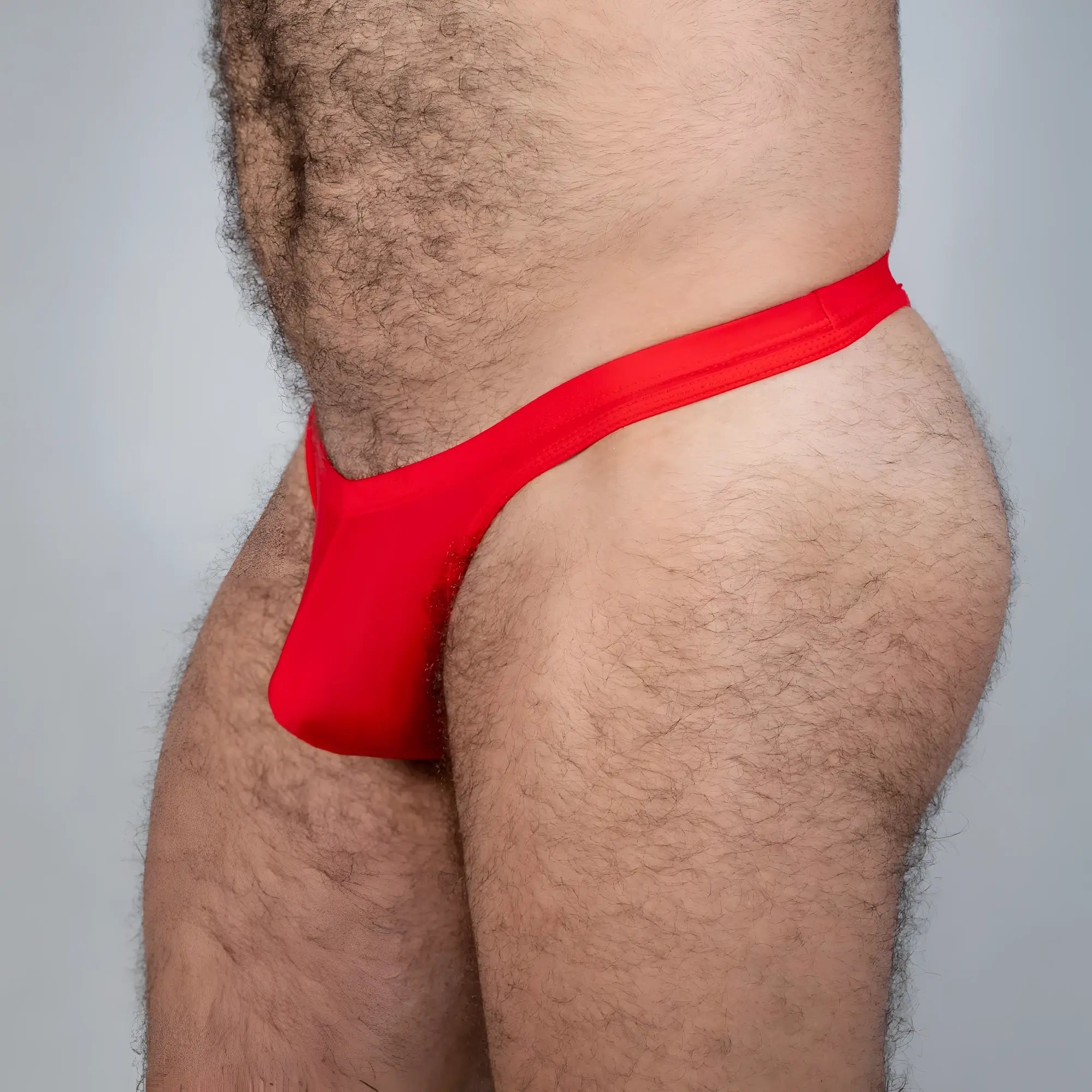 Red tulio swim thong made of smooth stretchy fabric shown from the back in a form-fitting solid design