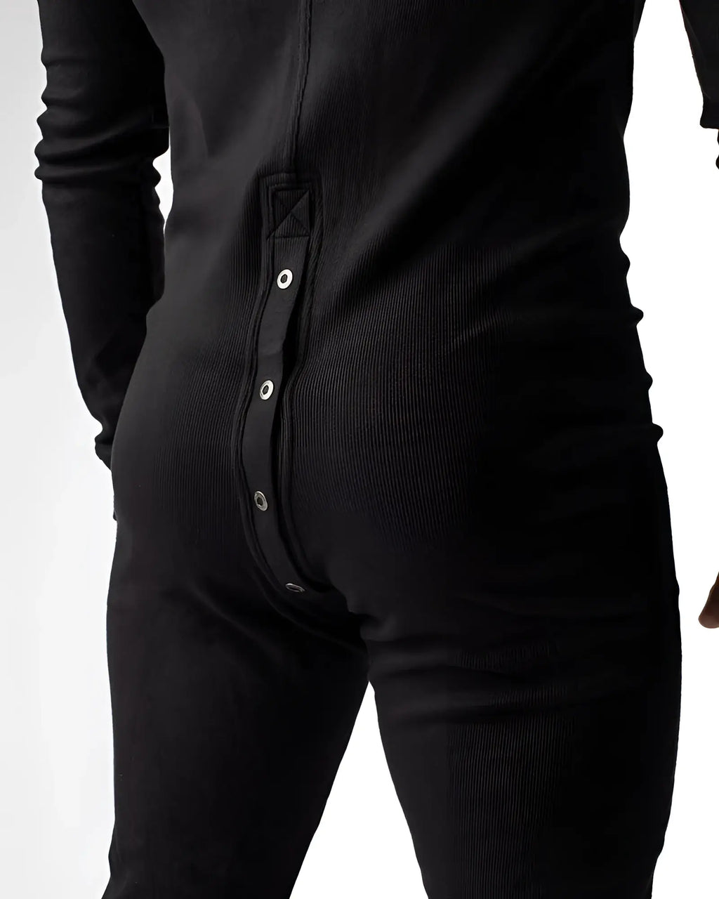 Black ribbed knit union suit one-piece pajama shown from back with vertical silver snap buttons down center