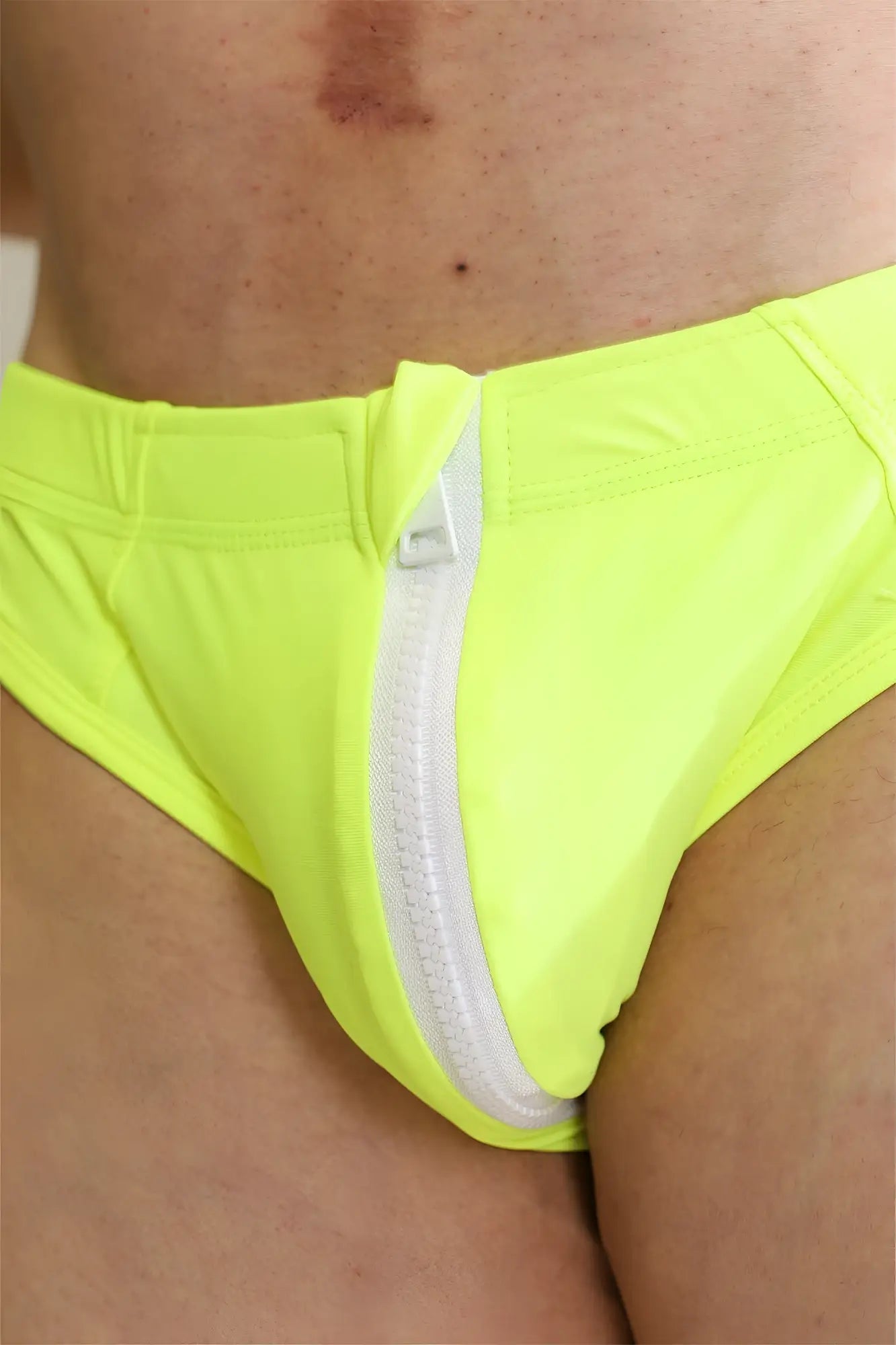 Neon yellow unzip me swim briefs featuring a white front zipper designed for vibrant beachwear use