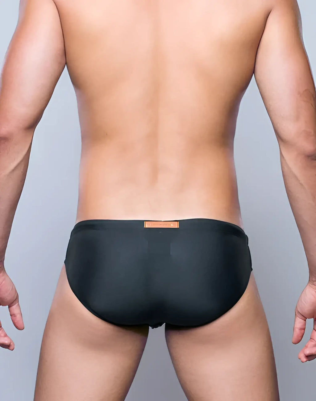 Black V10 core bikini swim trunks with a small orange label at the waistband, designed for swimming and beach use