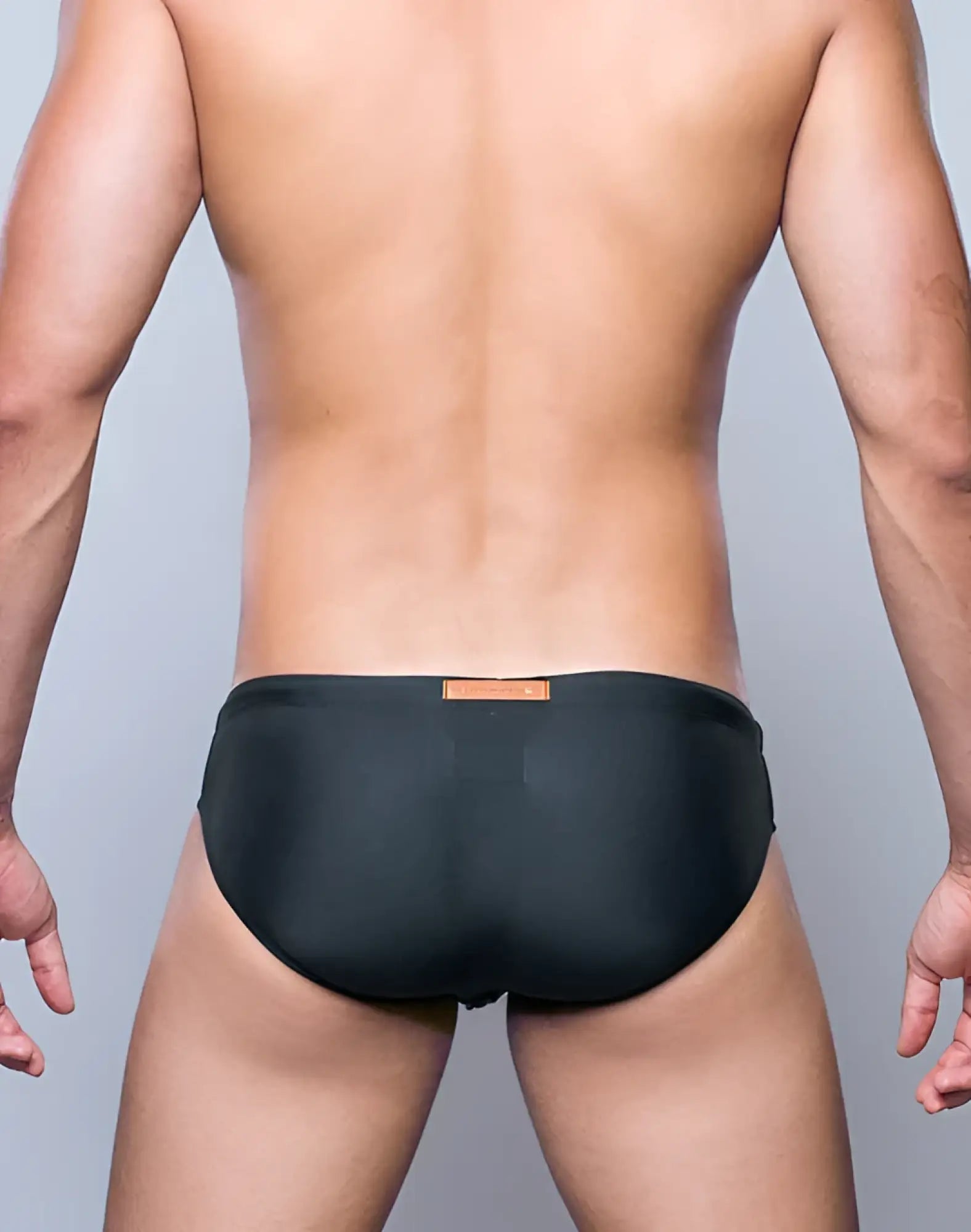 Black V10 core bikini swim trunks with a small orange label at the waistband, designed for swimming and beach use