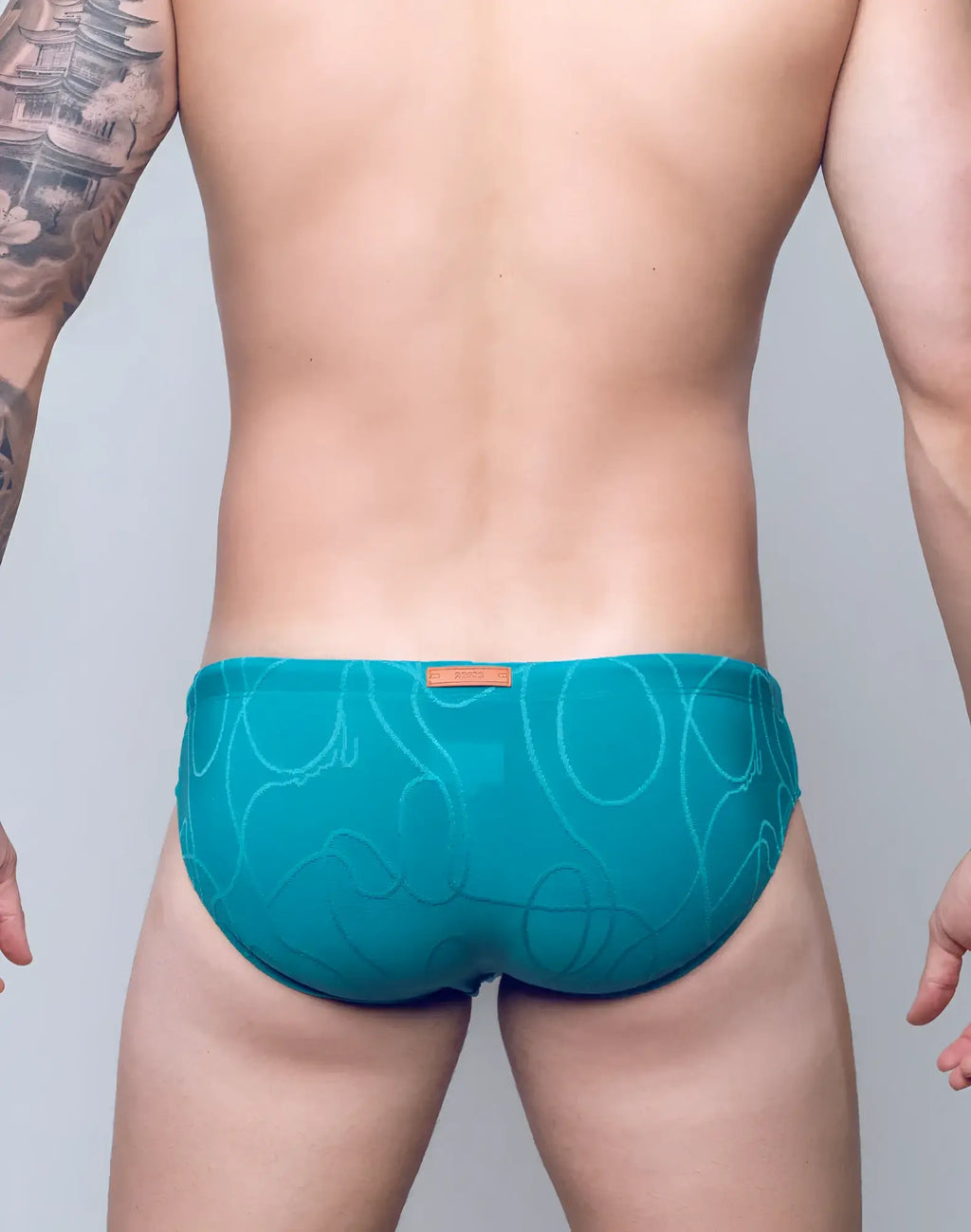 Teal v10 ripple textured swim brief with subtle abstract pattern and orange brand tag at the waistband