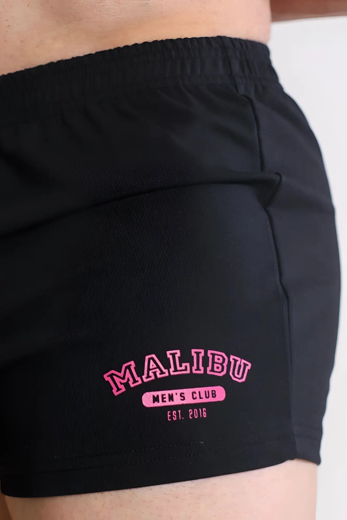 Black varsity 2 inch athletic shorts with pink embroidered malibu mens club logo and zipper pocket for versatility