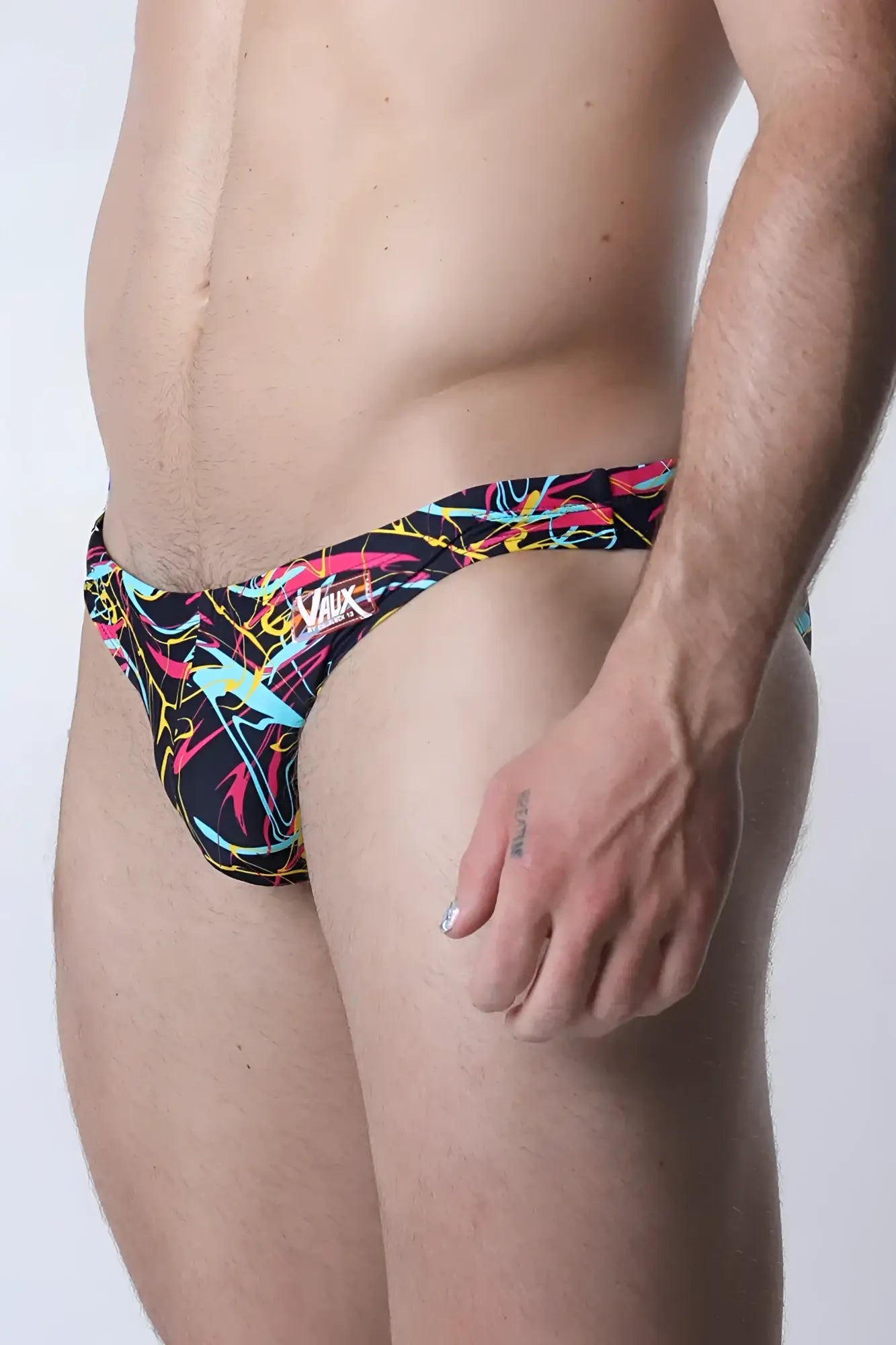 Vaux pulse swim brief men’s swim trunks with bold abstract neon pink yellow and cyan lines on black background