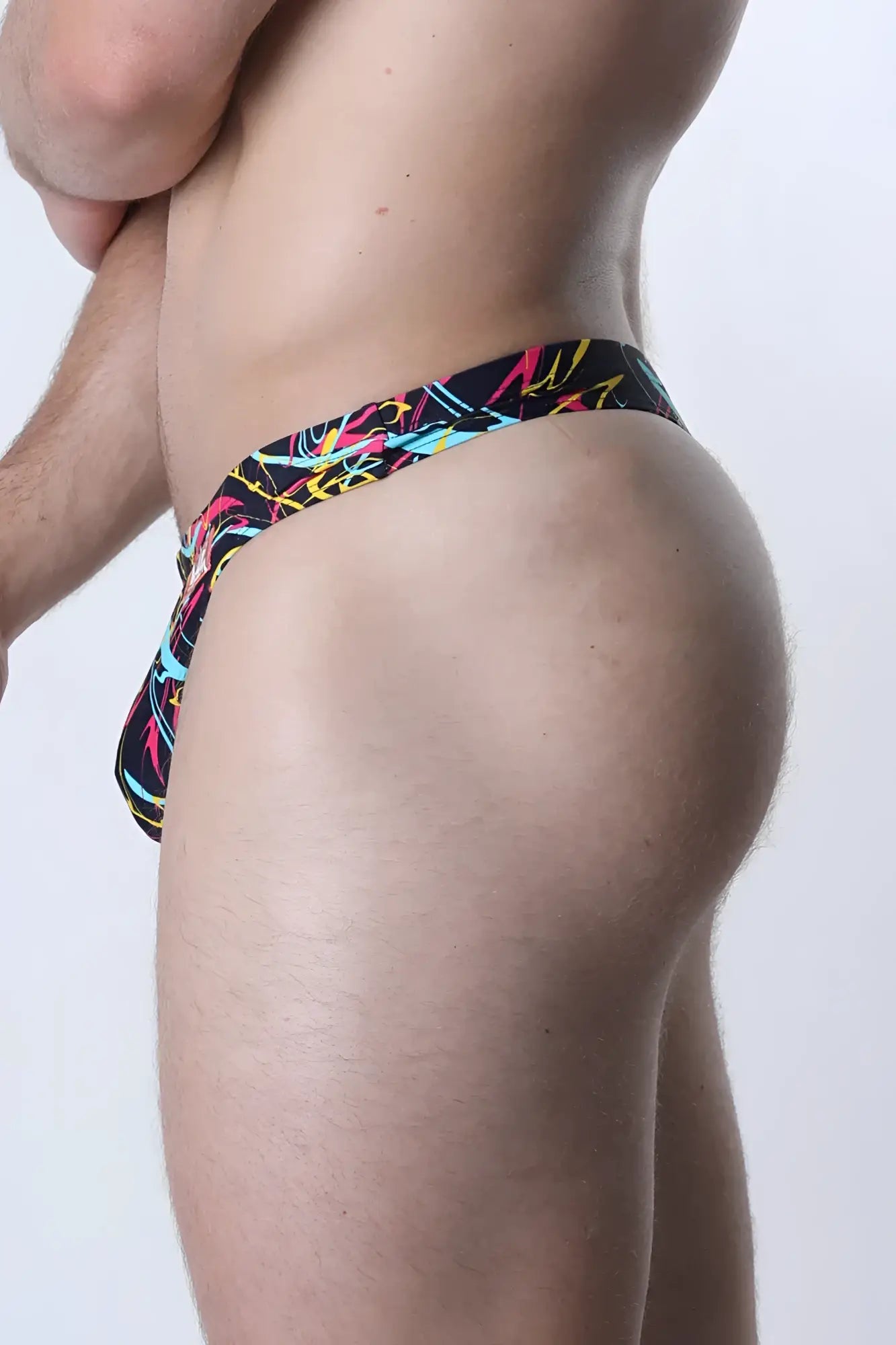 Vibrant graffiti-style patterned black pulse swim thong with neon pink yellow and cyan accents for bold swimwear look