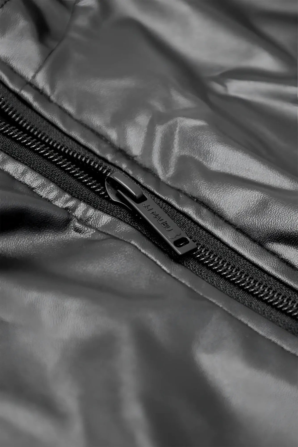 Black vegan leather zipper bodysuit featuring a sleek metallic pull tab on a shiny quilted jacket panel