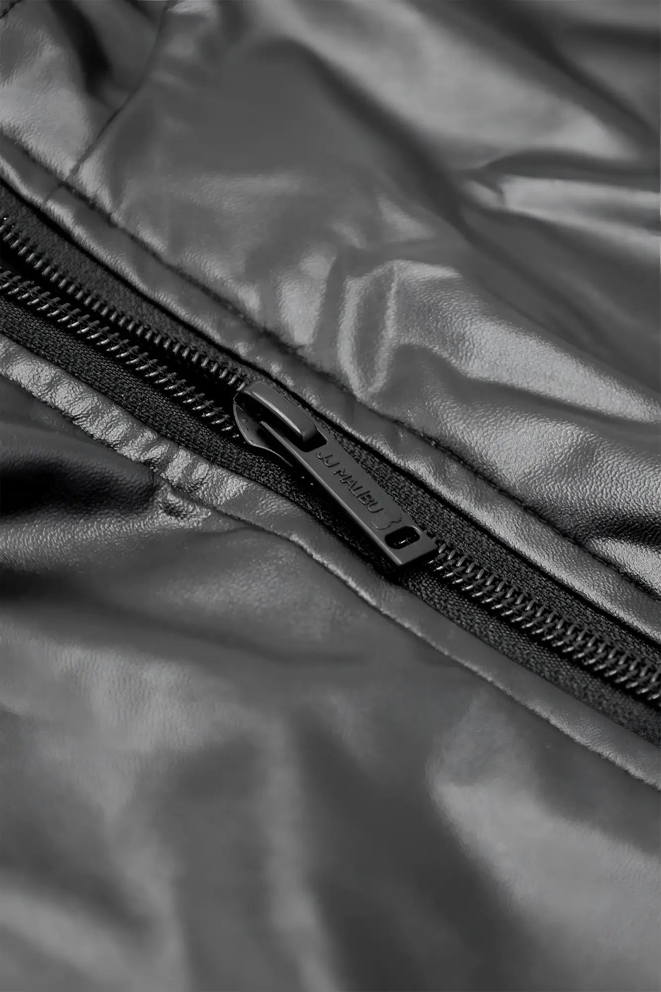 Black vegan leather zipper bodysuit featuring a sleek metallic pull tab on a shiny quilted jacket panel