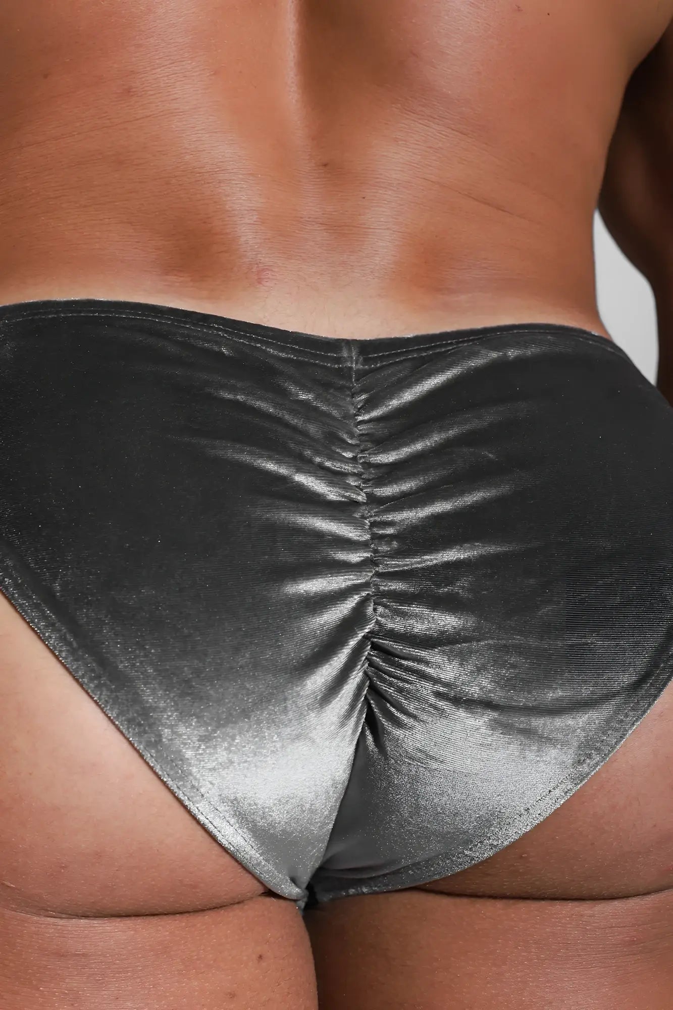 Velvety scrunch-butt bikini briefs in shiny metallic silver ruched fabric showing the back side in fossil grey tone