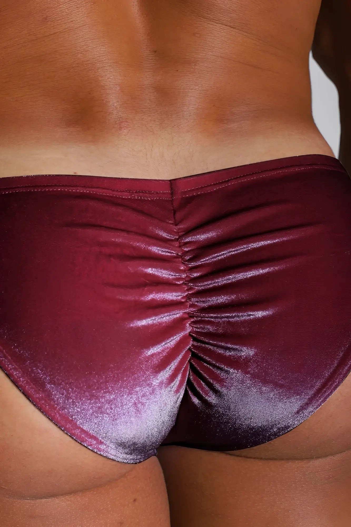 Maroon metallic satin bikini briefs with a ruched back design shown from the back side