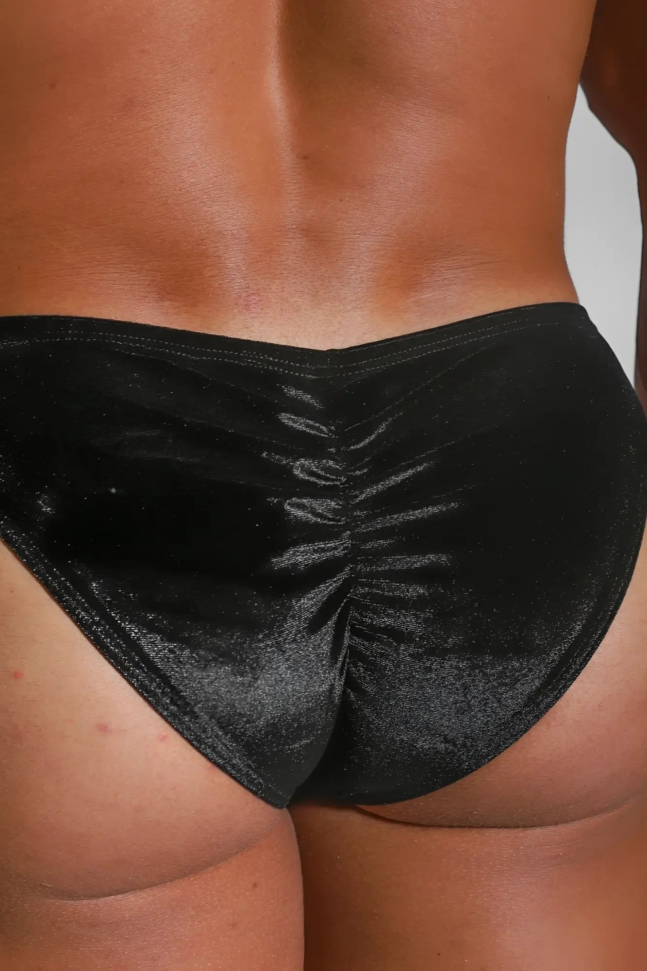 Black velvet bikini briefs with ruched back design showing the back side in onyx black velvety scrunch-butt style