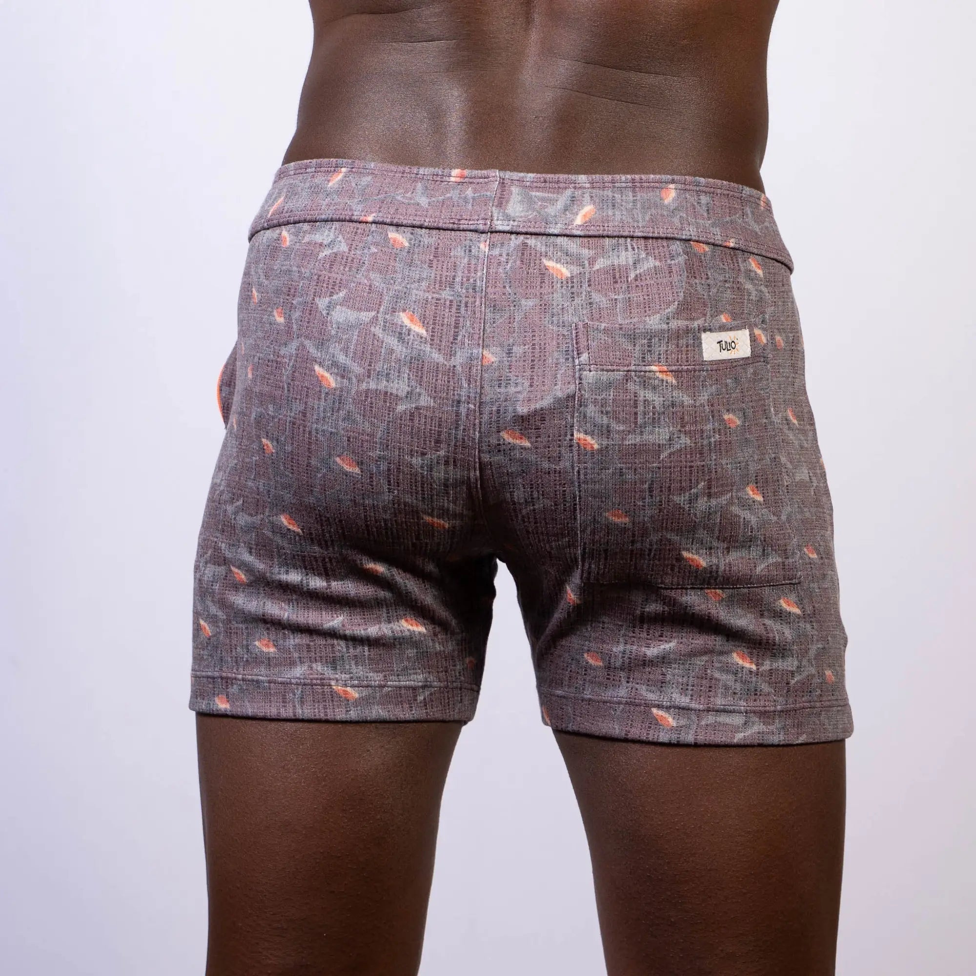 Back view of vintage stripes linen texture shorts in gray with subtle weave and orange fish motifs with branded label
