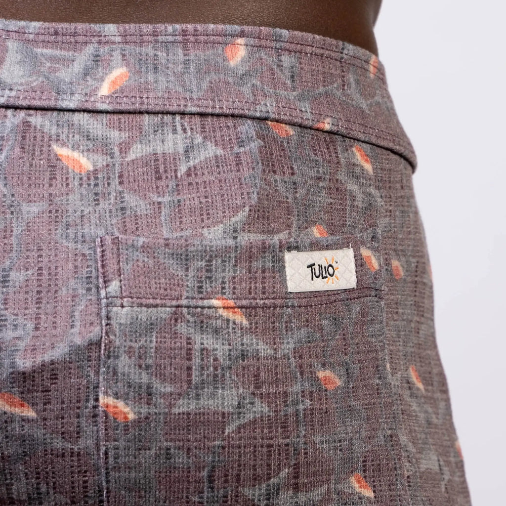 Back view of vintage stripes linen texture shorts in purple and gray with orange leaf accents and tulo label