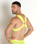 Vibrant neon yellow vinyl mesh harness underwear with strappy design and crisscross back shown from the back side