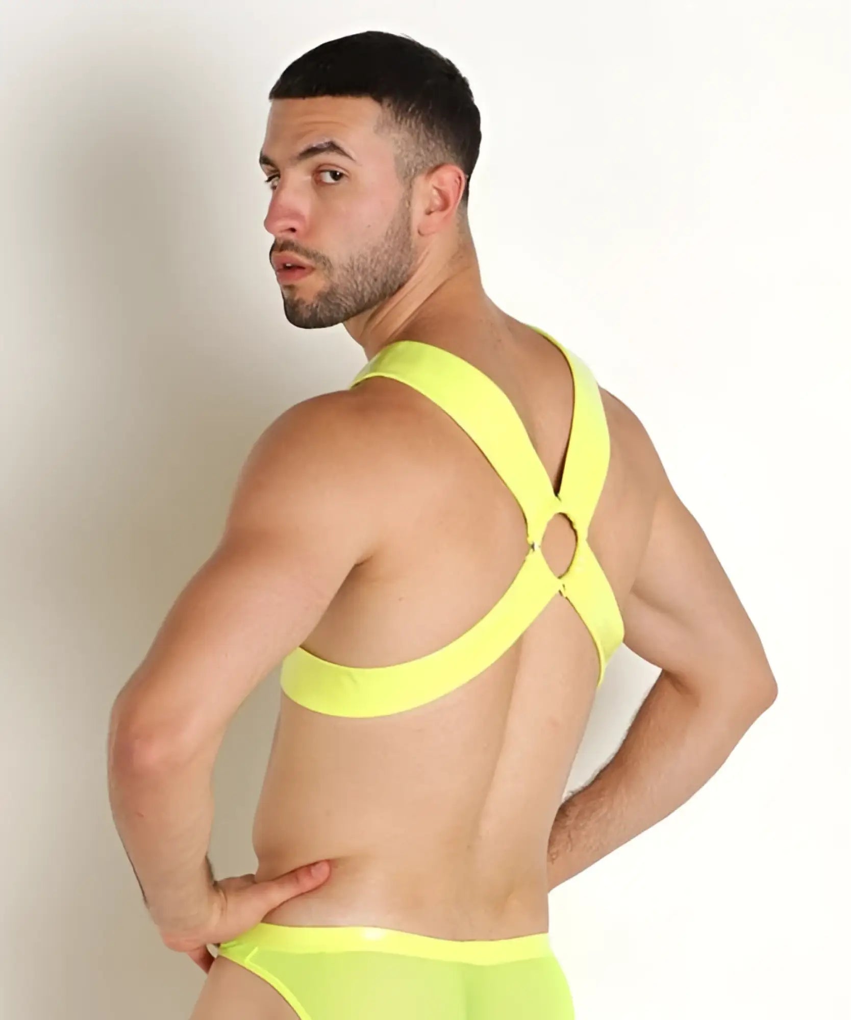 Vibrant neon yellow vinyl mesh harness underwear with strappy design and crisscross back shown from the back side