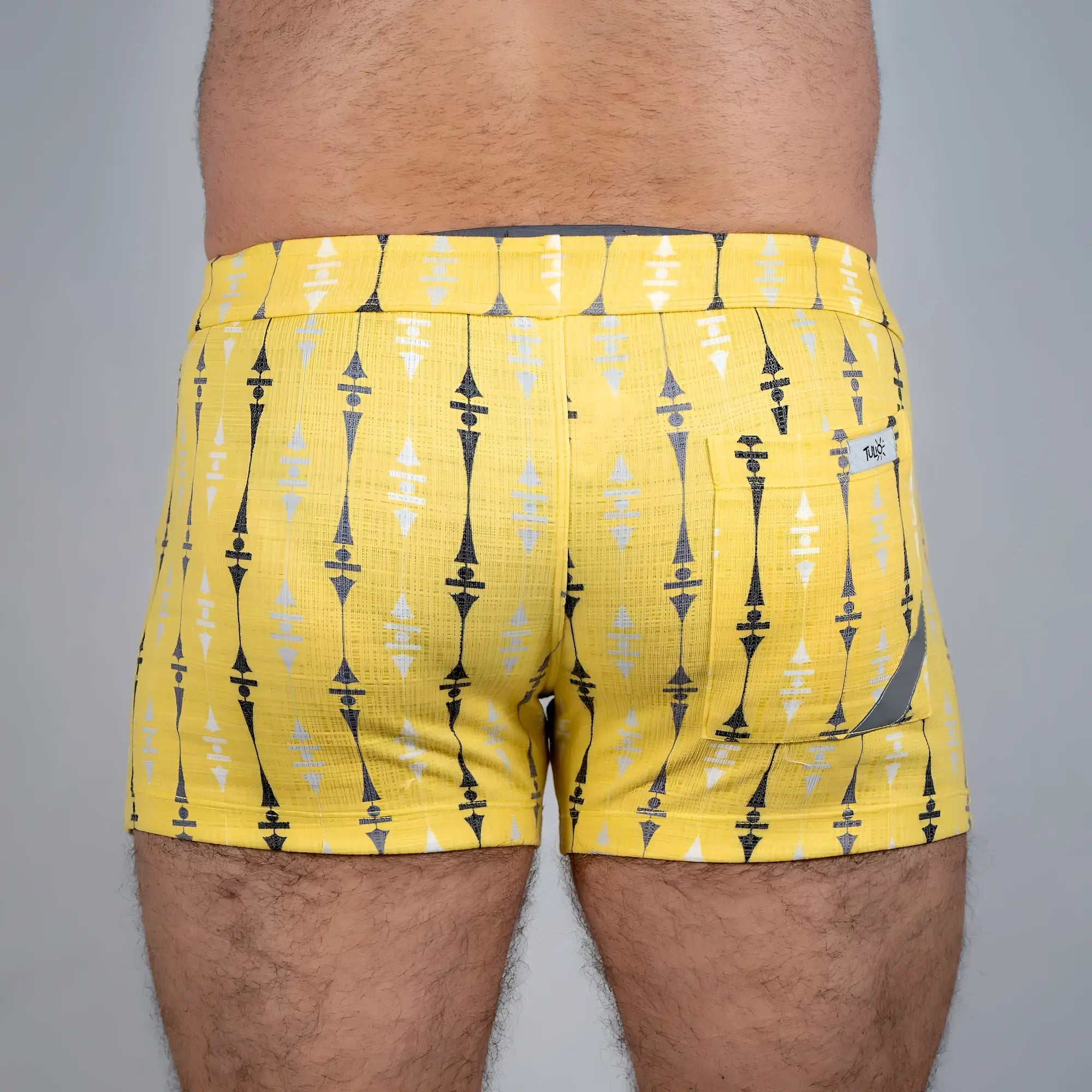 Bright yellow wallpaper print linen texture shorts with bold black and white geometric pattern and a back pocket tag visible