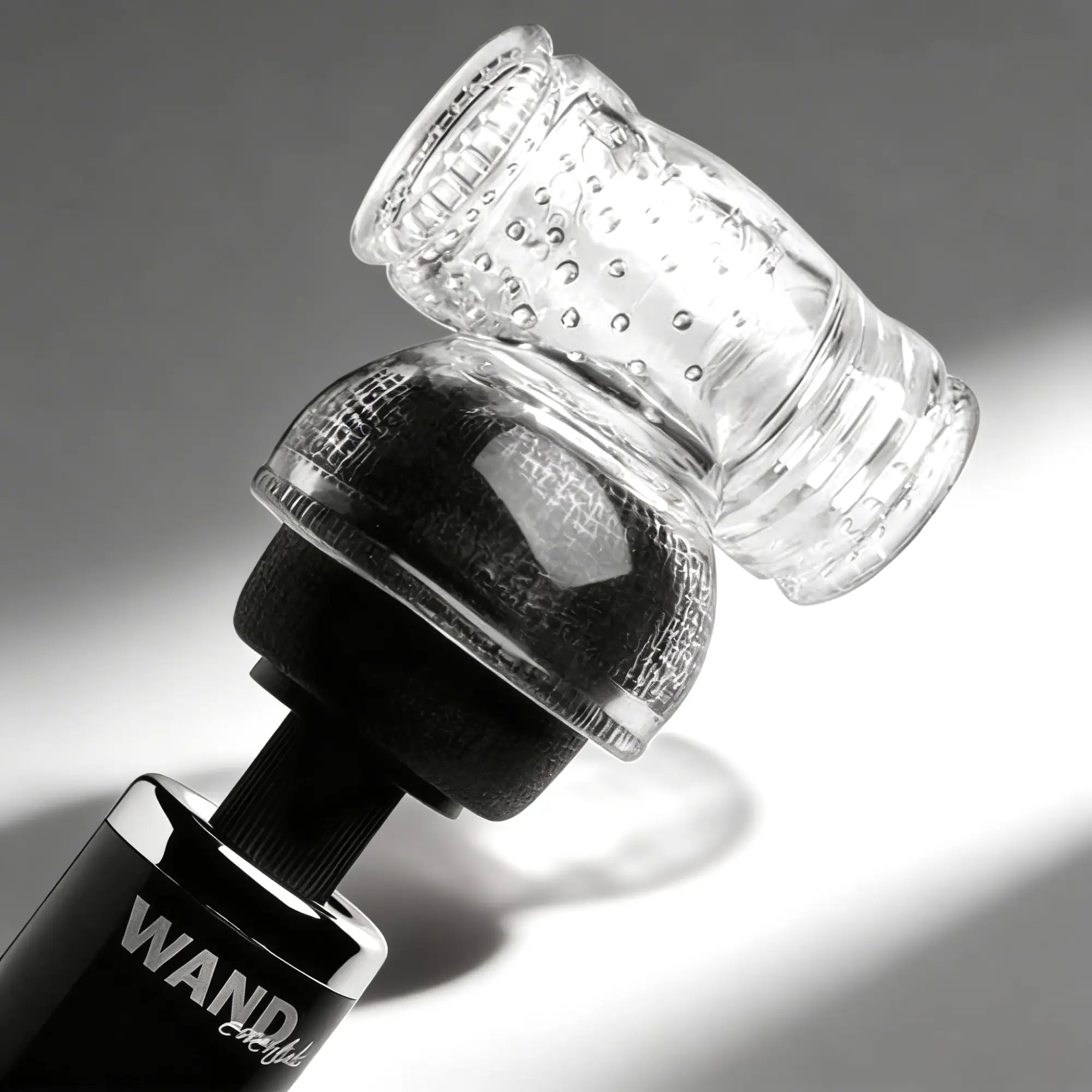 Wand Essentials Soft Masturbation Sleeve attached to a black wand massager head, featuring a clear, textured design.